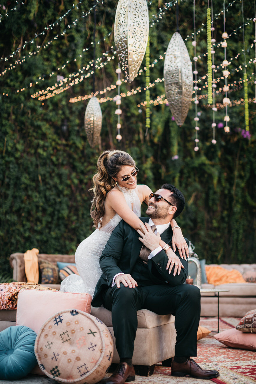 A bride hugs her sitting groom from behind in their Persian Destination Wedding in Antigua