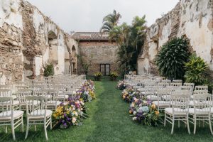 Wedding Ceremony with white chairs face an altar with yellow and purple flowers next to the chairs. 